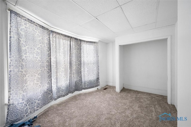 spare room featuring carpet and a drop ceiling