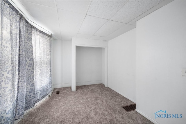 basement featuring a paneled ceiling and carpet flooring