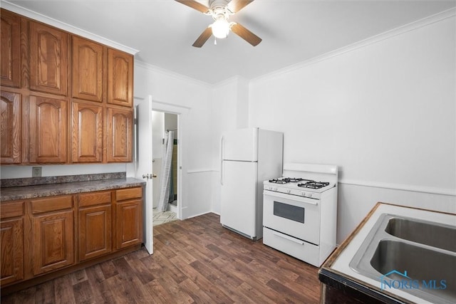 kitchen with white appliances, sink, ceiling fan, crown molding, and dark wood-type flooring