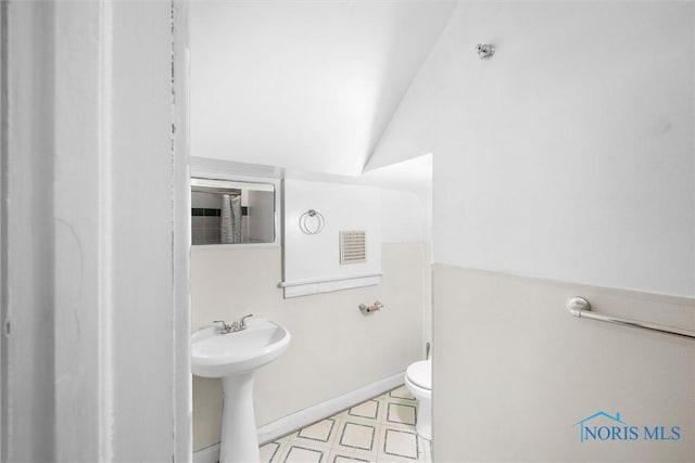 bathroom featuring sink, toilet, and lofted ceiling