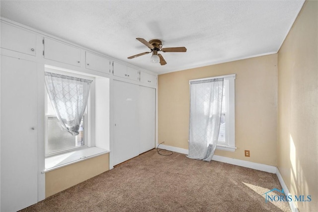 unfurnished bedroom with a textured ceiling, ceiling fan, and light colored carpet