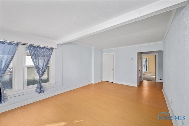 unfurnished room featuring ornamental molding, hardwood / wood-style flooring, beamed ceiling, and a wealth of natural light