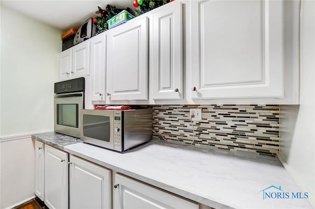 4811 Larkhaven Dr, Toledo, OH 43623 - kitchen with stainless steel oven, white cabinets, tasteful backsplash, and light countertops