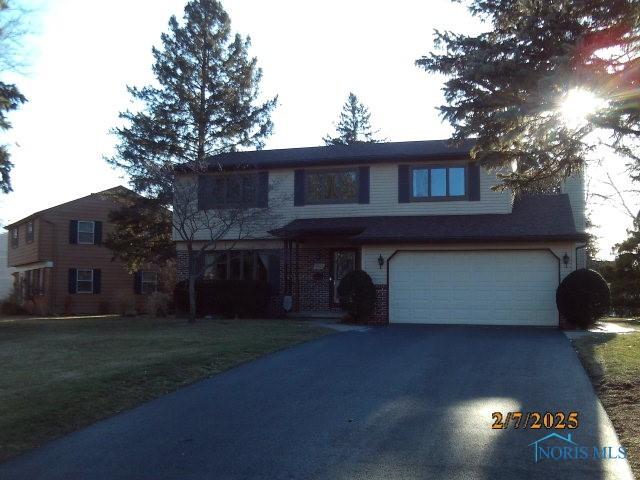 traditional-style home with a garage, driveway, and a front lawn