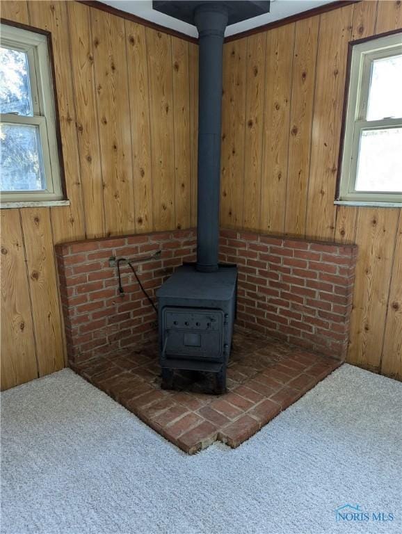 room details featuring carpet flooring, a wood stove, and wood walls