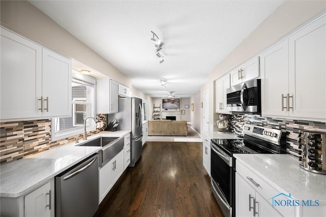 kitchen featuring sink, light stone counters, stainless steel appliances, white cabinets, and tasteful backsplash