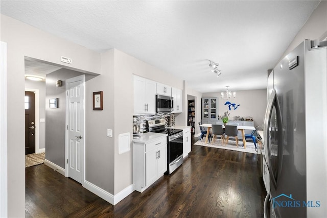 kitchen featuring dark hardwood / wood-style flooring, stainless steel appliances, white cabinetry, and backsplash