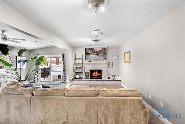 living room with a brick fireplace and ceiling fan