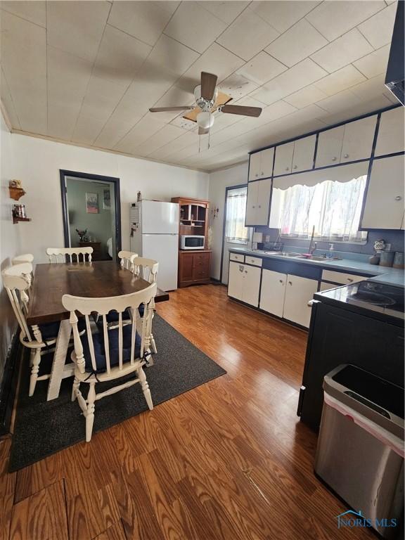 kitchen featuring white fridge, wood-type flooring, sink, white cabinetry, and ceiling fan