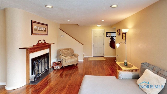 living area featuring baseboards, a glass covered fireplace, wood finished floors, and recessed lighting