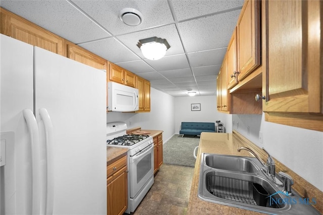 kitchen with light countertops, white appliances, a drop ceiling, and a sink