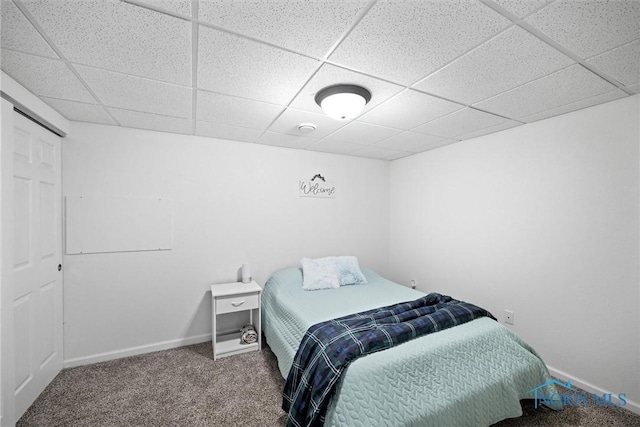 carpeted bedroom with a paneled ceiling and baseboards