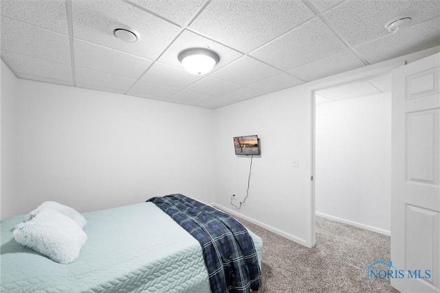 bedroom with carpet floors, baseboards, and a paneled ceiling