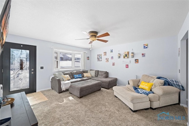 living room featuring light colored carpet, ceiling fan, baseboards, and light tile patterned floors