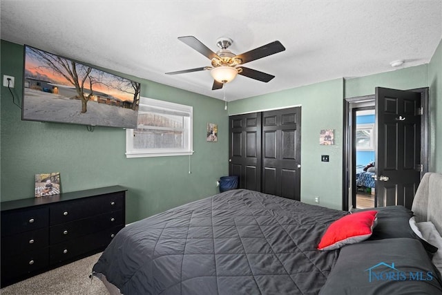 bedroom featuring a textured ceiling, ceiling fan, a closet, and carpet flooring