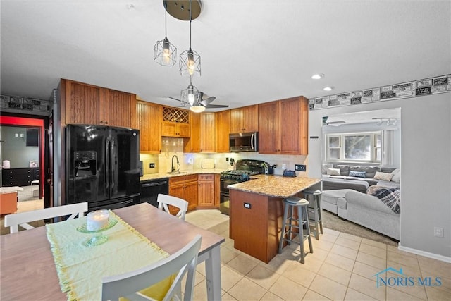 kitchen featuring ceiling fan, black appliances, a breakfast bar area, and a sink