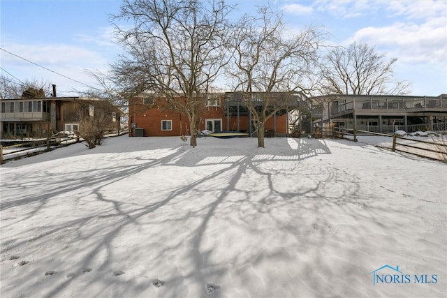 snow covered property featuring a residential view and fence