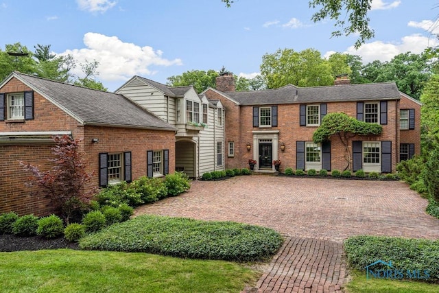 colonial inspired home with brick siding and roof with shingles