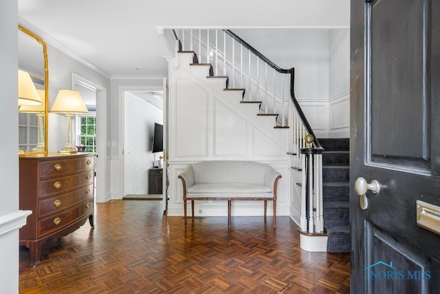 foyer entrance with crown molding, stairs, and a decorative wall