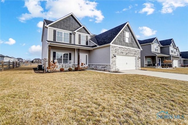 craftsman house with fence, stone siding, driveway, a residential view, and a front lawn