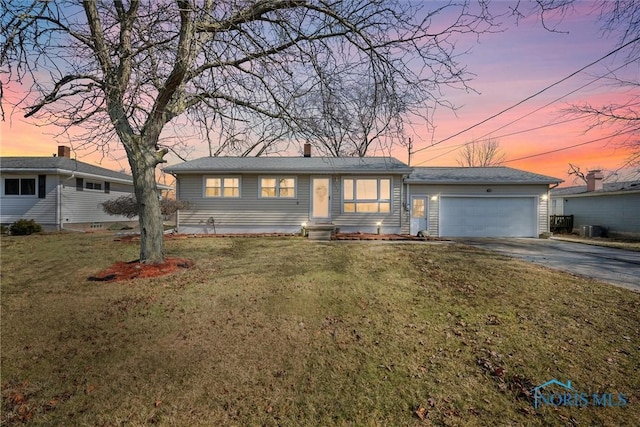 ranch-style home with driveway, a yard, an attached garage, and entry steps