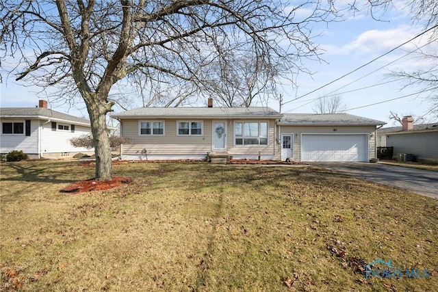 ranch-style home featuring entry steps, driveway, an attached garage, and a front yard