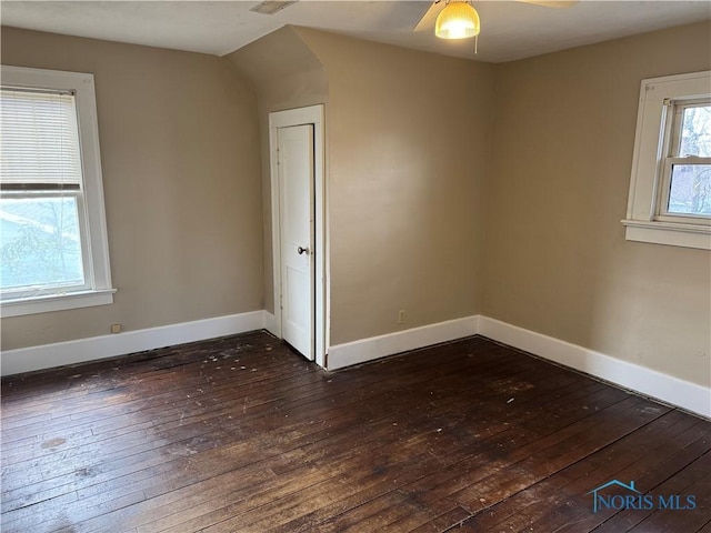 empty room featuring dark wood-type flooring, baseboards, and a ceiling fan