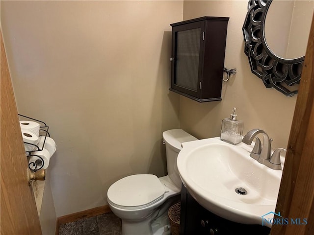 half bath featuring toilet, baseboards, and vanity