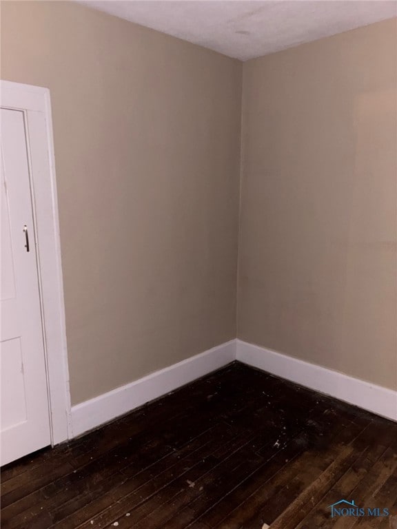 unfurnished room with dark wood-style flooring and baseboards