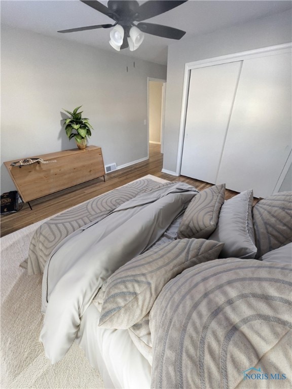 bedroom with a closet, hardwood / wood-style flooring, and ceiling fan