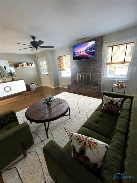 living room featuring a fireplace, ceiling fan, hardwood / wood-style floors, and plenty of natural light