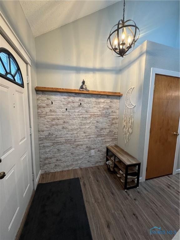 entryway featuring lofted ceiling, a textured ceiling, wood finished floors, and an inviting chandelier