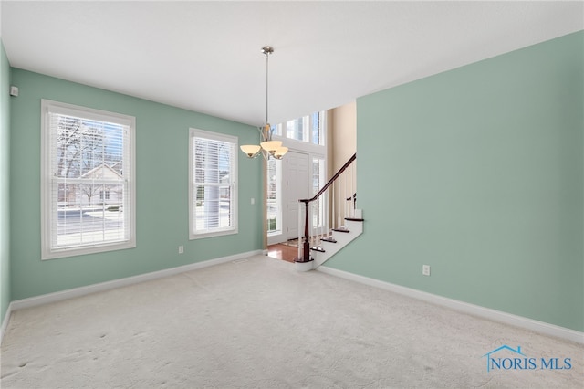 carpeted spare room with a chandelier, stairs, and baseboards