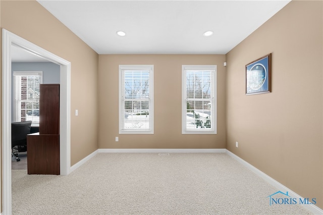 empty room featuring light carpet, plenty of natural light, and baseboards