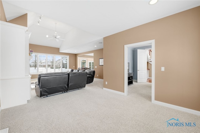 living room with vaulted ceiling, light carpet, a ceiling fan, and baseboards