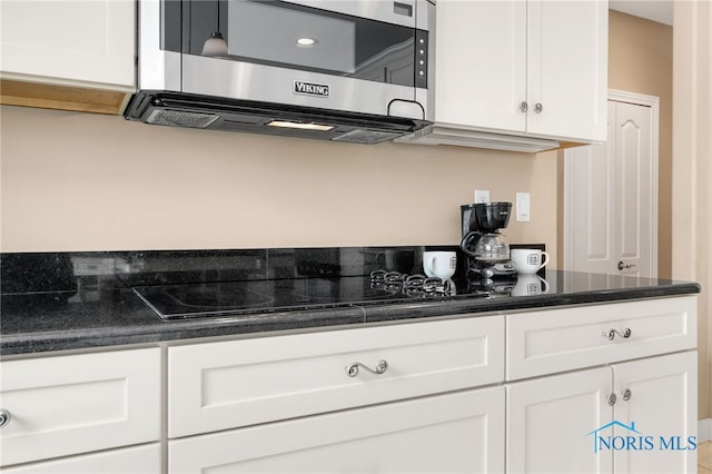 kitchen featuring white cabinets, dark countertops, and stainless steel microwave