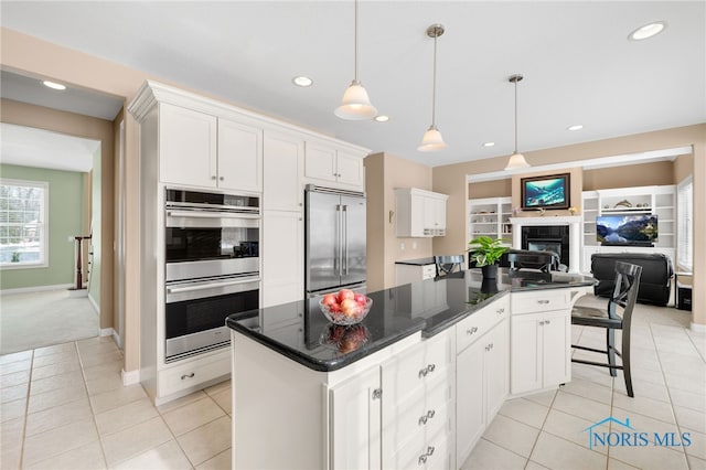 kitchen featuring open floor plan, stainless steel appliances, a center island, and white cabinets