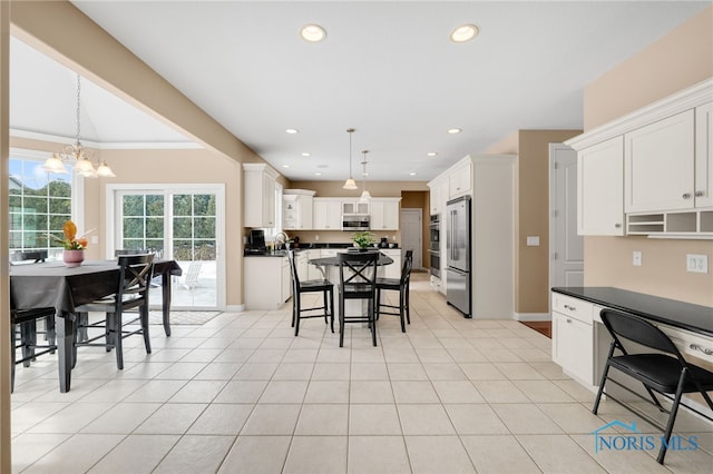 kitchen with dark countertops, appliances with stainless steel finishes, white cabinetry, and pendant lighting