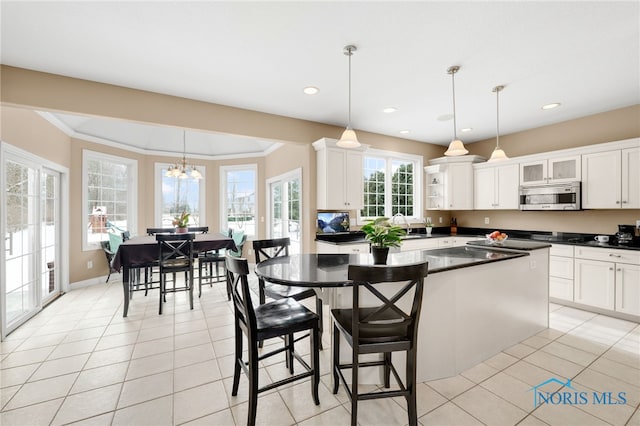 kitchen featuring white cabinets, decorative light fixtures, dark countertops, and stainless steel microwave