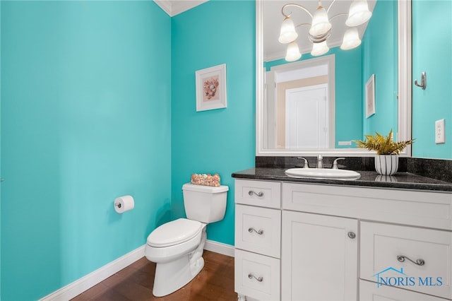 bathroom featuring wood finished floors, ornamental molding, toilet, and vanity