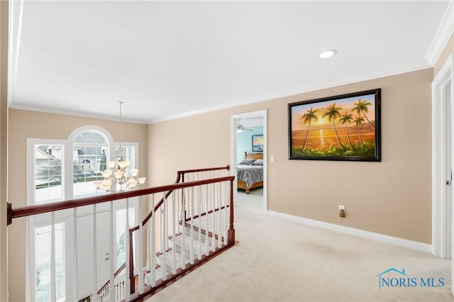 hallway with ornamental molding, light carpet, an upstairs landing, and baseboards