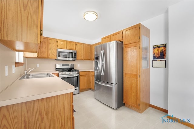 kitchen featuring light floors, light countertops, stainless steel appliances, baseboards, and a sink