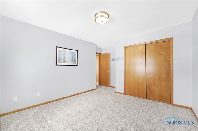 unfurnished bedroom with light carpet, baseboards, and a closet