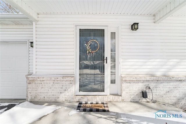 view of exterior entry featuring brick siding and an attached garage