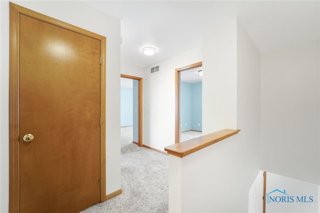 hall with light carpet, baseboards, and visible vents