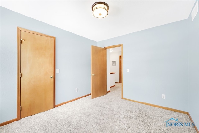 unfurnished bedroom featuring light carpet and baseboards