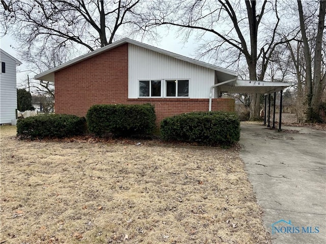 view of property exterior featuring an attached carport, concrete driveway, and brick siding