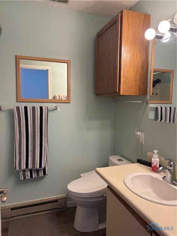 half bathroom with toilet, visible vents, baseboard heating, and vanity