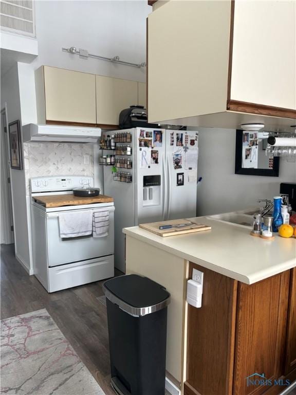 kitchen featuring under cabinet range hood, white appliances, visible vents, light countertops, and dark wood finished floors