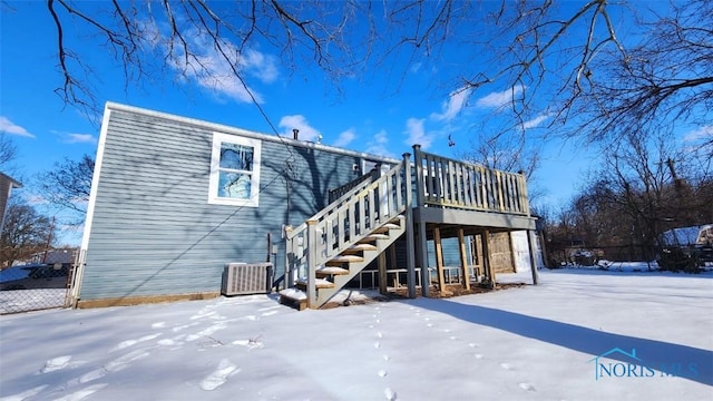 snow covered back of property featuring central air condition unit, stairs, and a deck